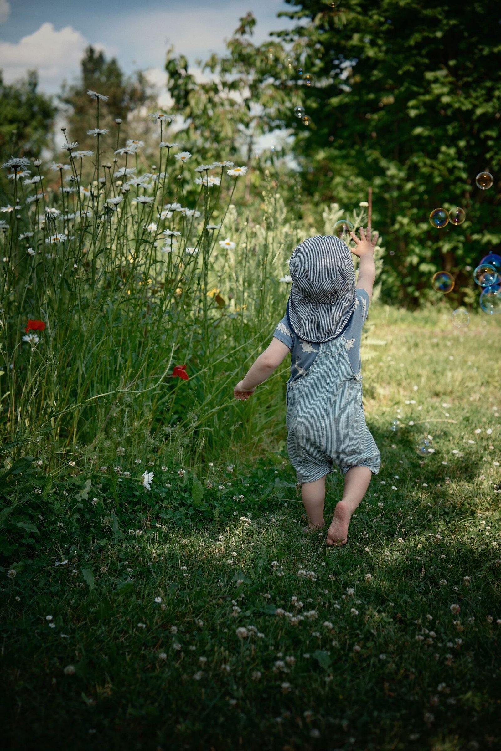 Kind läuft durch hohes Gras in einem sonnigen Garten