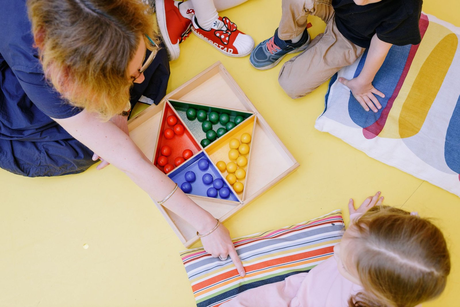 Kinderhände sortieren bunte Steine bei einem Lernspiel